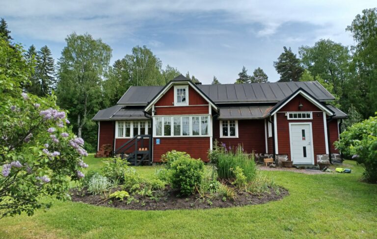 Punatiilen värinen maalaistalo, Skatan tila. Ympärillä vehreän vihreä luonto.